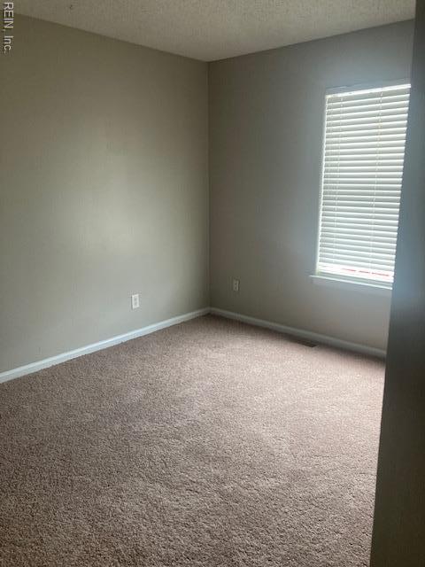 unfurnished room with carpet floors, baseboards, and a textured ceiling