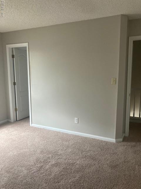 spare room featuring baseboards, carpet flooring, and a textured ceiling