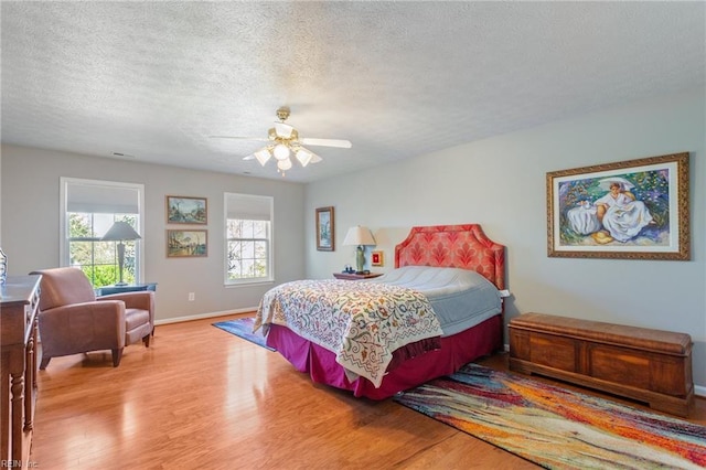 bedroom with baseboards, a textured ceiling, wood finished floors, and a ceiling fan