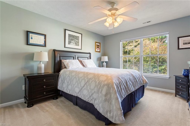 bedroom with baseboards, visible vents, a ceiling fan, and light carpet