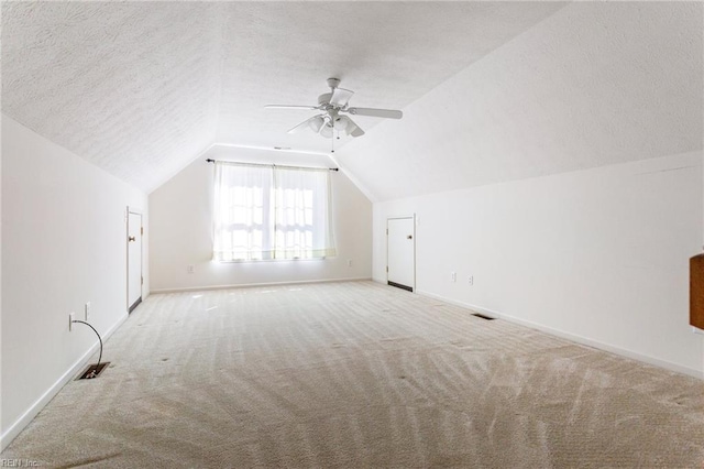 additional living space featuring carpet flooring, a textured ceiling, baseboards, a ceiling fan, and lofted ceiling