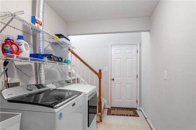laundry room with washing machine and dryer, baseboards, laundry area, and a textured ceiling