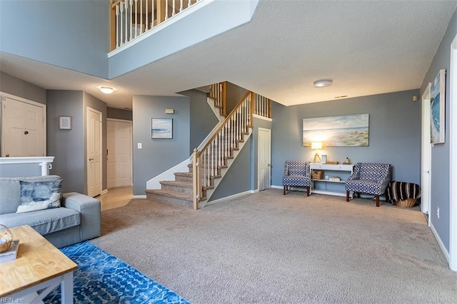 living area with stairs, carpet floors, baseboards, and a textured ceiling