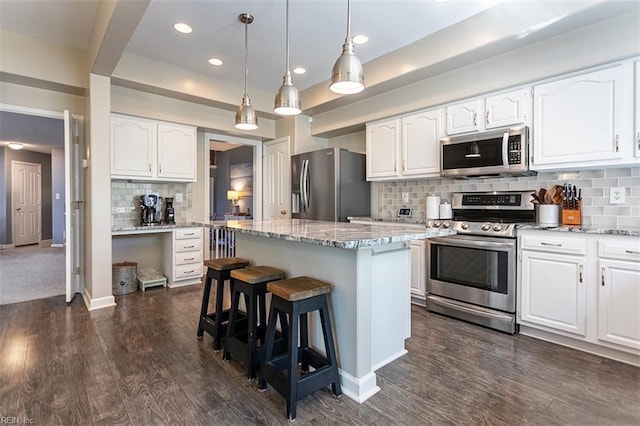 kitchen featuring a kitchen breakfast bar, light stone countertops, appliances with stainless steel finishes, dark wood-style floors, and a center island