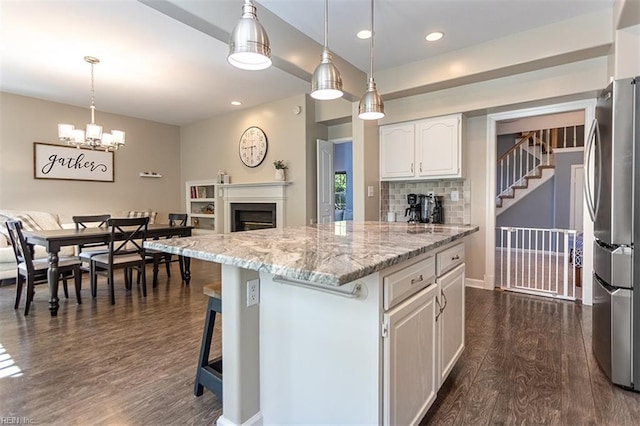 kitchen featuring freestanding refrigerator, a fireplace, light stone countertops, dark wood finished floors, and white cabinets