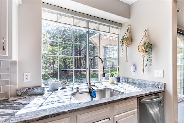 kitchen with a sink, white cabinetry, light stone counters, and dishwasher
