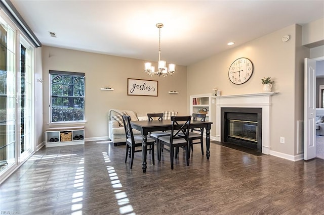 dining space with a fireplace with flush hearth, baseboards, wood finished floors, and a chandelier