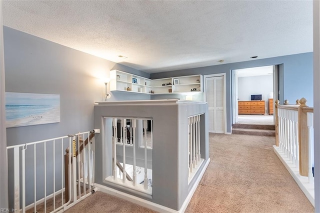 corridor with carpet flooring, an upstairs landing, and a textured ceiling