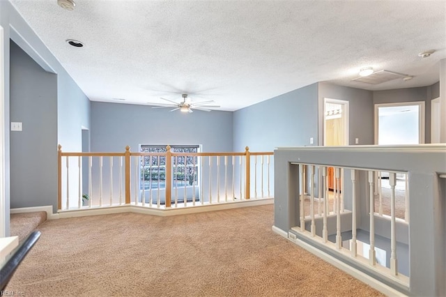 hallway with carpet flooring, a textured ceiling, an upstairs landing, and a wealth of natural light
