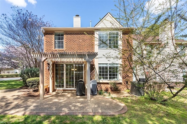 rear view of property featuring a chimney, brick siding, a pergola, and a patio