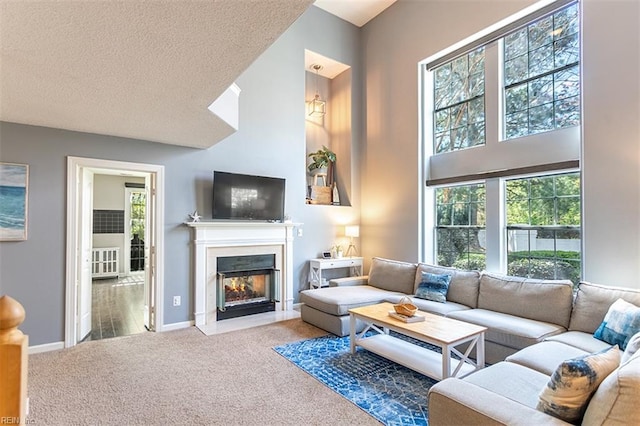 living area featuring a fireplace with flush hearth, baseboards, a textured ceiling, a high ceiling, and carpet floors