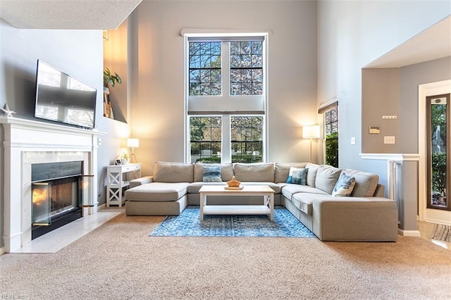 carpeted living area with a towering ceiling and a tile fireplace
