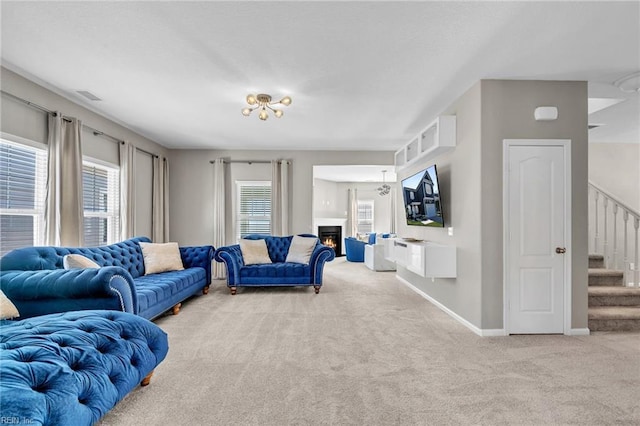 living room featuring carpet, a warm lit fireplace, visible vents, stairs, and baseboards