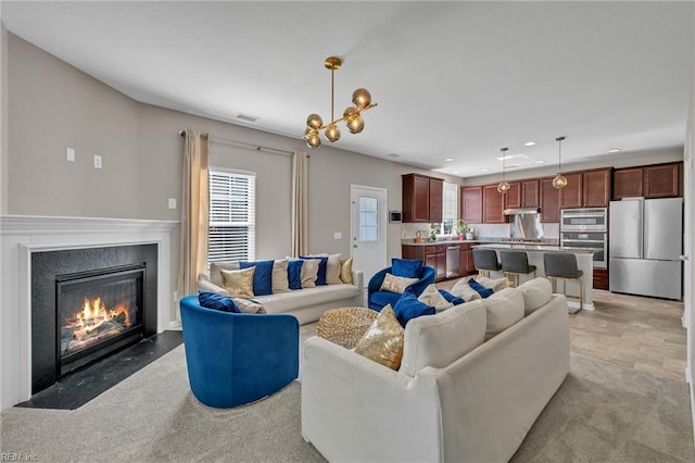 living area featuring a fireplace, recessed lighting, a notable chandelier, and visible vents