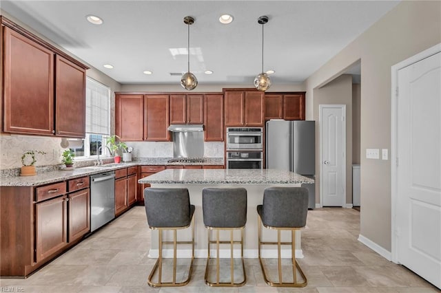 kitchen with a kitchen breakfast bar, a kitchen island, light stone countertops, decorative backsplash, and appliances with stainless steel finishes