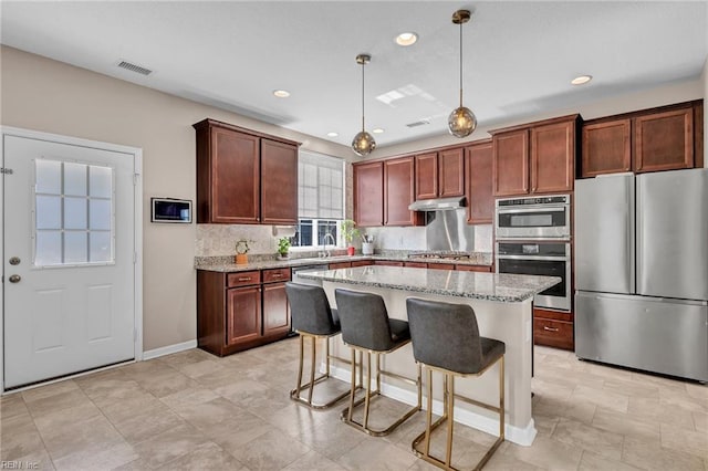 kitchen with visible vents, light stone countertops, appliances with stainless steel finishes, and under cabinet range hood
