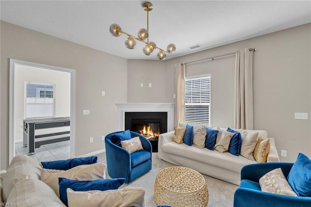 carpeted living room with a chandelier, baseboards, a glass covered fireplace, and visible vents