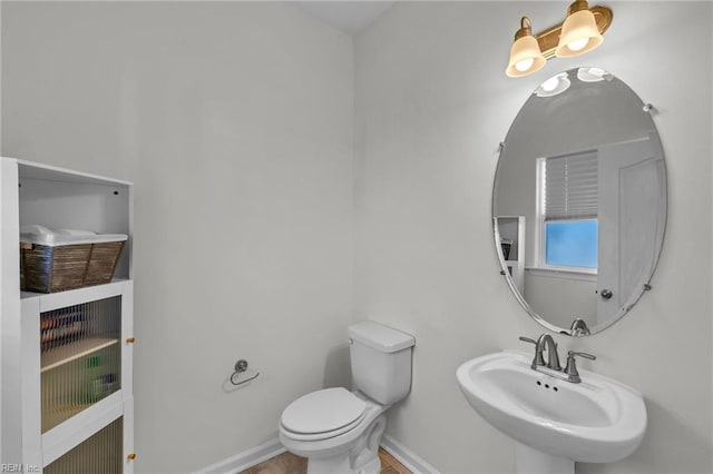 bathroom with a sink, toilet, and baseboards