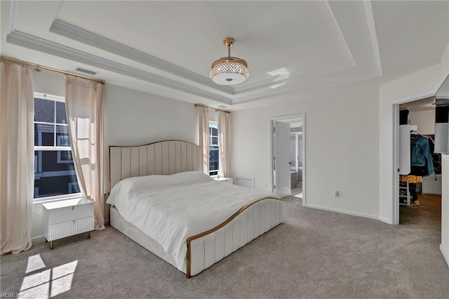 carpeted bedroom featuring crown molding, a tray ceiling, a walk in closet, and visible vents