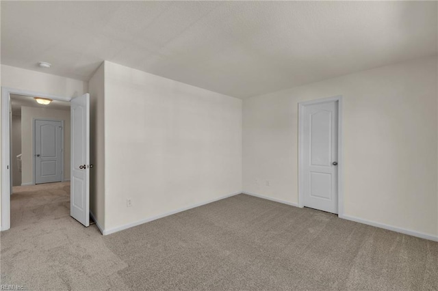 unfurnished room featuring light colored carpet and baseboards