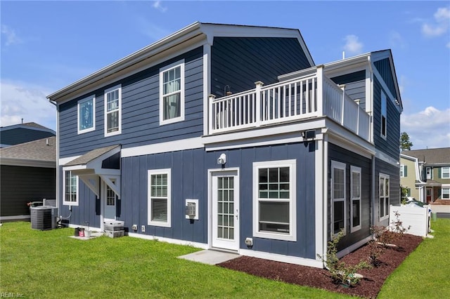 rear view of property featuring central AC unit, a balcony, board and batten siding, and a lawn