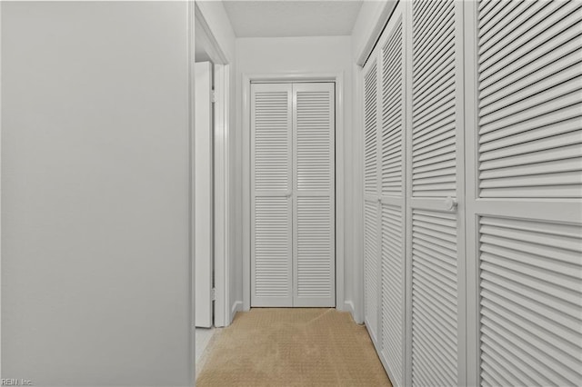 hallway featuring light colored carpet