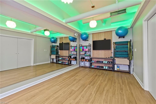 rec room with baseboards, visible vents, wood finished floors, and a raised ceiling