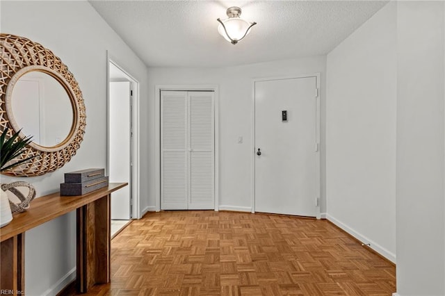 foyer featuring a textured ceiling and baseboards