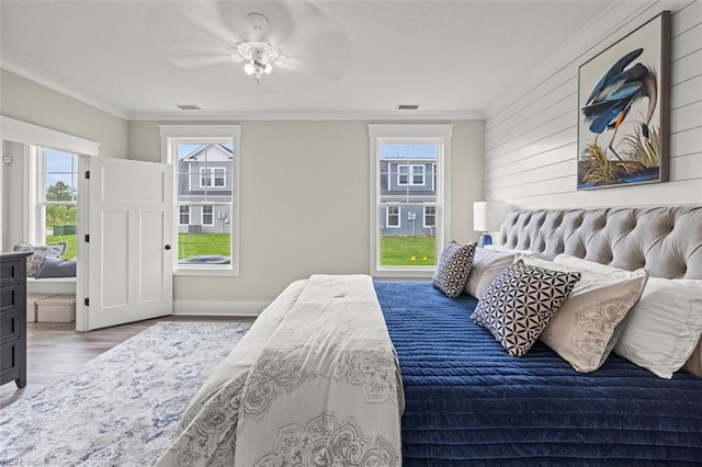 bedroom featuring visible vents, wood finished floors, ceiling fan, and ornamental molding