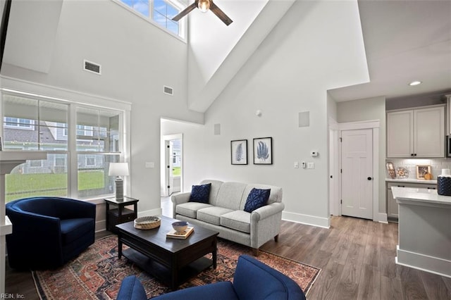 living room with baseboards, visible vents, wood finished floors, and a ceiling fan