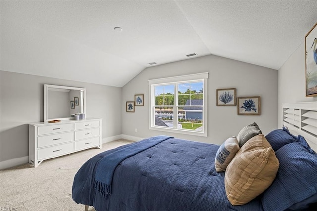 bedroom with a textured ceiling, visible vents, baseboards, lofted ceiling, and light colored carpet