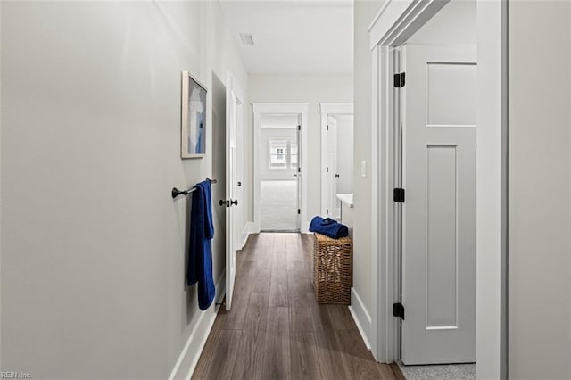 hallway with baseboards, visible vents, and dark wood-style flooring