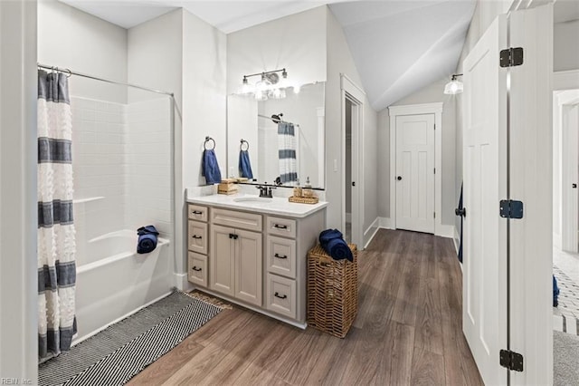 full bath featuring lofted ceiling, shower / bathtub combination with curtain, wood finished floors, and vanity