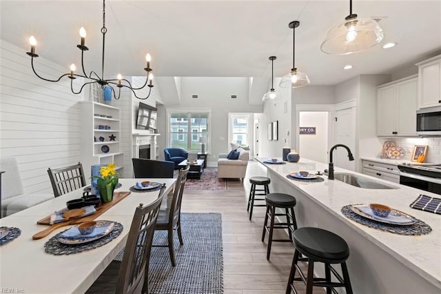 kitchen featuring a sink, a kitchen bar, open floor plan, stainless steel appliances, and decorative backsplash
