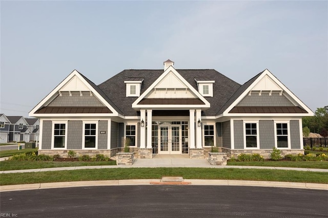 craftsman-style home with stone siding, metal roof, a chimney, a standing seam roof, and french doors