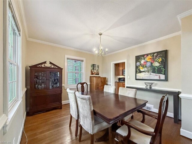 dining area featuring baseboards, a notable chandelier, crown molding, and wood finished floors