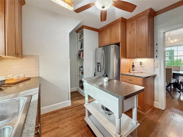 kitchen featuring a sink, light wood-style floors, stainless steel fridge, and open shelves
