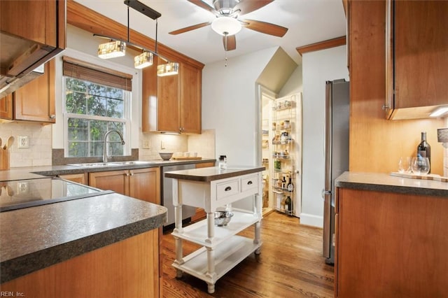 kitchen featuring stainless steel appliances, decorative backsplash, a sink, dark countertops, and ceiling fan