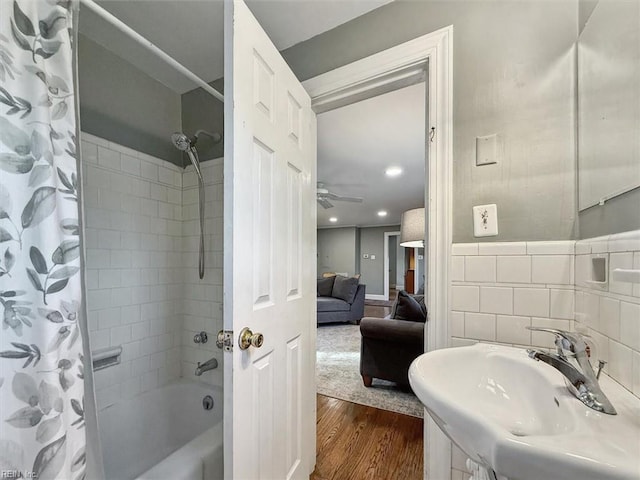 full bath featuring tile walls, shower / tub combo with curtain, a sink, ensuite bath, and wood finished floors