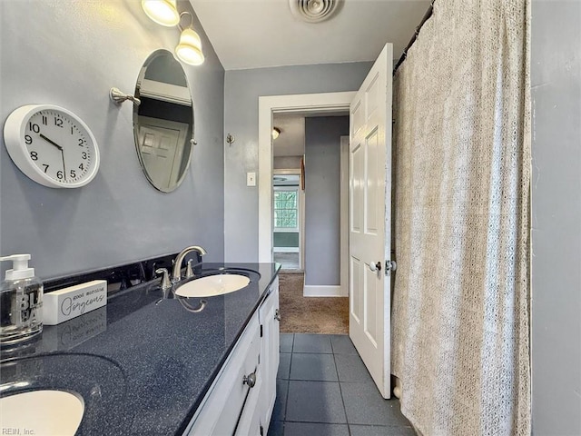 full bath featuring tile patterned flooring, baseboards, a sink, visible vents, and double vanity