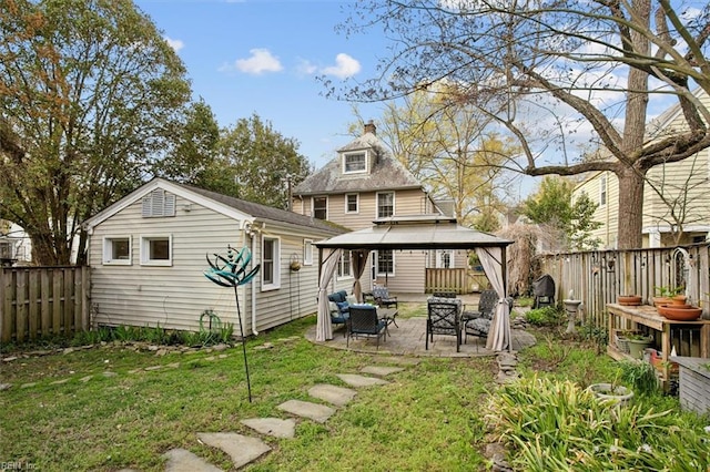 back of property with a patio, a chimney, a fenced backyard, a gazebo, and a lawn