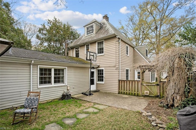 rear view of property with a gate, fence, a patio, a chimney, and a lawn