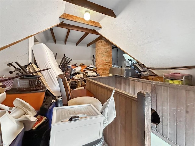 interior space featuring vaulted ceiling with beams and a textured wall