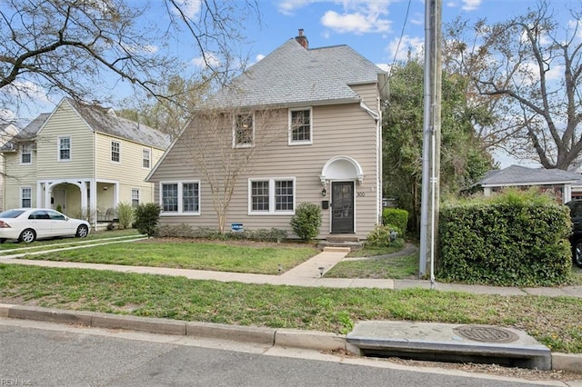 view of front of property with a chimney and a front lawn