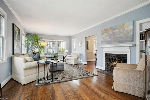 living area with a warm lit fireplace, crown molding, baseboards, and wood finished floors