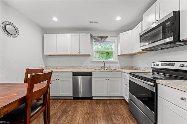kitchen featuring dark wood-type flooring, white cabinets, appliances with stainless steel finishes, light countertops, and a sink