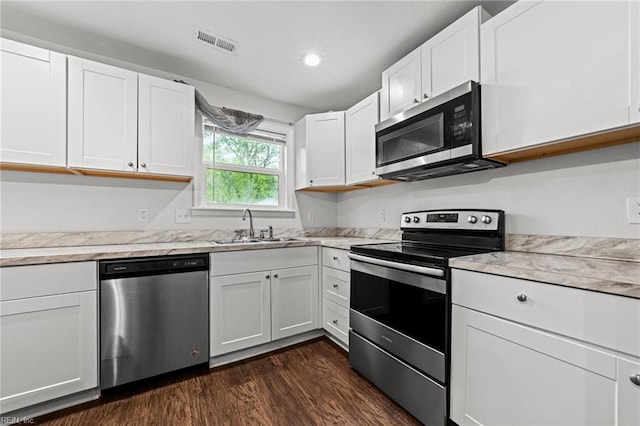 kitchen featuring visible vents, white cabinets, a sink, dark wood-style flooring, and stainless steel appliances