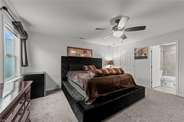bedroom with ensuite bathroom, baseboards, a ceiling fan, and light carpet