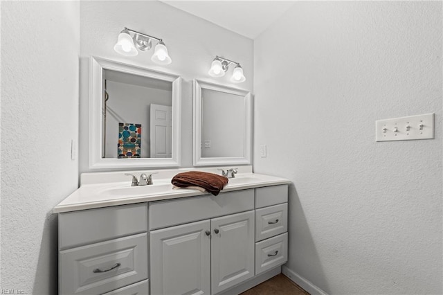 bathroom with a textured wall, double vanity, and a sink