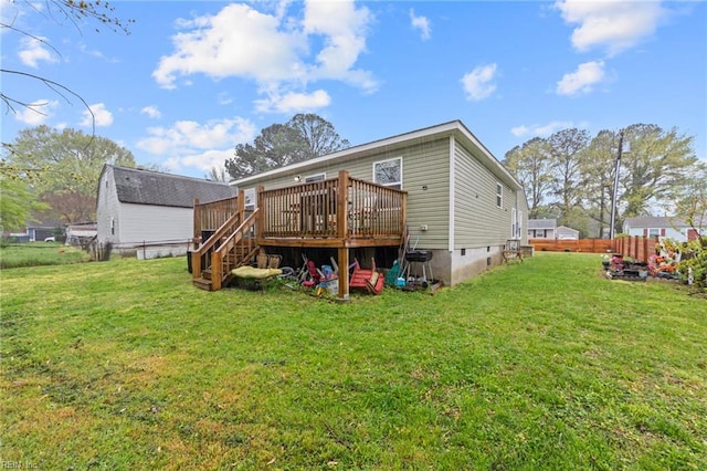 back of property featuring a deck, fence, and a lawn
